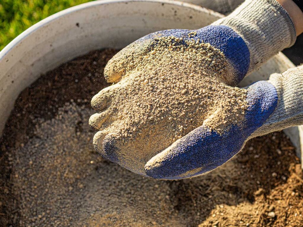 Manos con guantes sosteniendo fertilizante natural Rocket Fuel