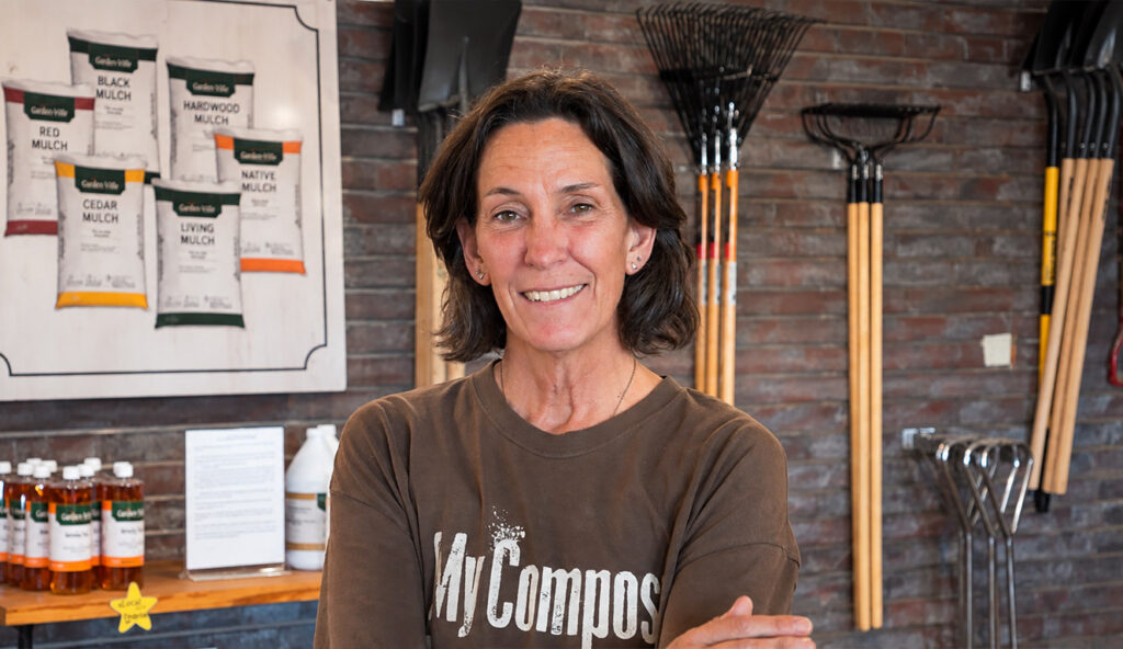 Garden-Ville team member in the store with bagged mulch and garden tools